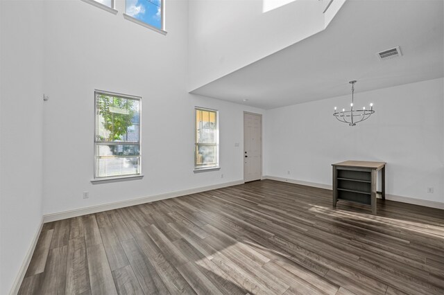 unfurnished living room with hardwood / wood-style flooring, a chandelier, and a high ceiling