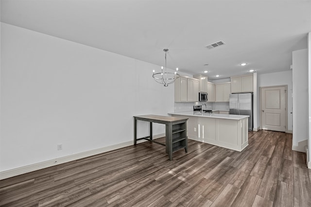 kitchen featuring kitchen peninsula, hanging light fixtures, stainless steel appliances, white cabinets, and dark wood-type flooring