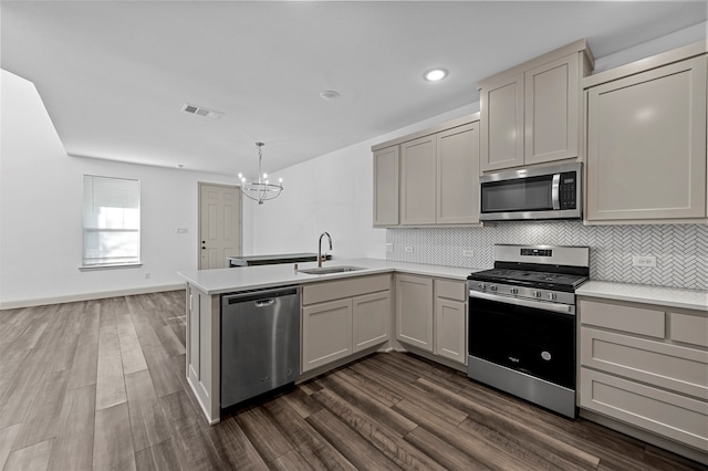 kitchen with appliances with stainless steel finishes, sink, pendant lighting, and dark hardwood / wood-style flooring