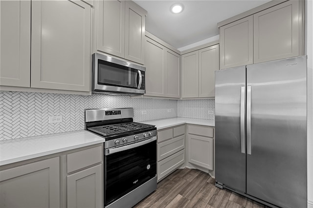 kitchen with gray cabinets, backsplash, stainless steel appliances, and dark hardwood / wood-style floors