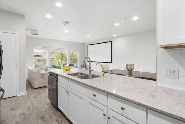 kitchen with tasteful backsplash, white cabinetry, light stone countertops, light hardwood / wood-style flooring, and sink