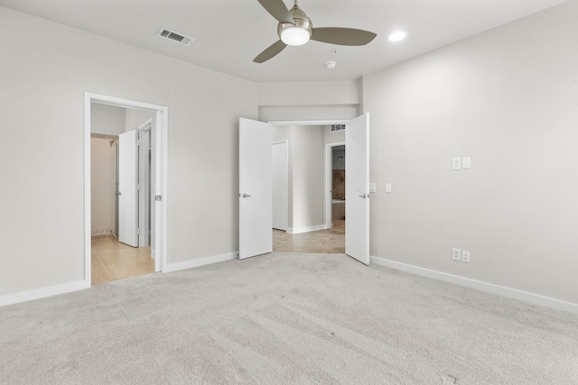 unfurnished bedroom featuring connected bathroom, light carpet, and ceiling fan