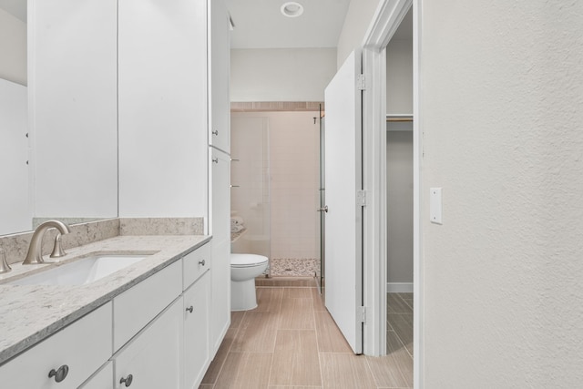 bathroom with toilet, vanity, and a shower with door