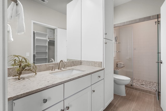 bathroom with a shower with door, vanity, and toilet