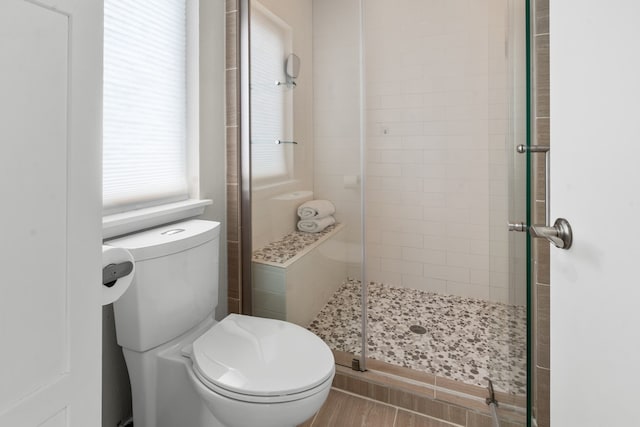 bathroom featuring toilet and a shower with shower door