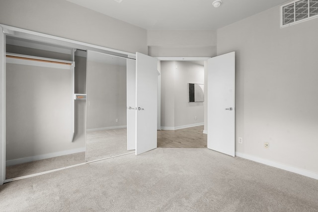 unfurnished bedroom featuring a closet and light carpet