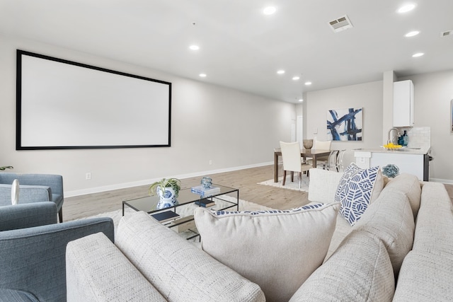 cinema room with light hardwood / wood-style floors and sink