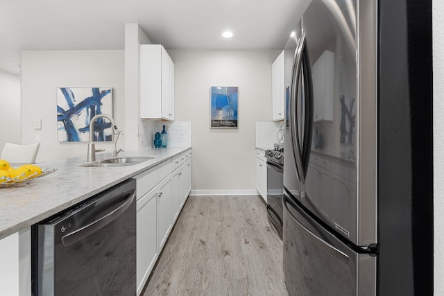 kitchen with decorative backsplash, stainless steel appliances, sink, light wood-type flooring, and white cabinetry