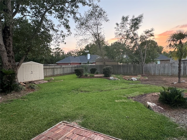 yard at dusk featuring a storage shed