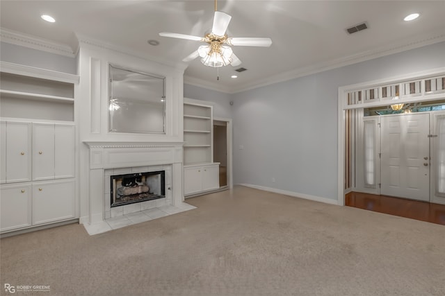 unfurnished living room featuring ornamental molding, light colored carpet, a tile fireplace, and ceiling fan