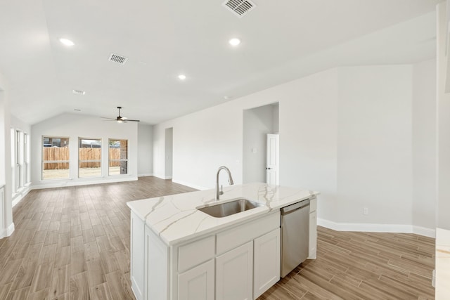 kitchen featuring an island with sink, sink, white cabinets, stainless steel dishwasher, and light stone counters