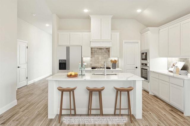 kitchen featuring sink, appliances with stainless steel finishes, an island with sink, light hardwood / wood-style floors, and white cabinets