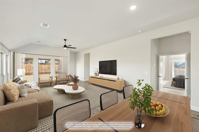 living room with hardwood / wood-style flooring, ceiling fan, and vaulted ceiling