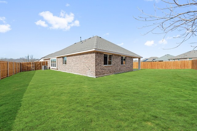 rear view of property featuring cooling unit and a lawn