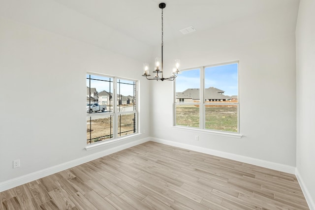 unfurnished dining area featuring a notable chandelier, a wealth of natural light, and light hardwood / wood-style floors