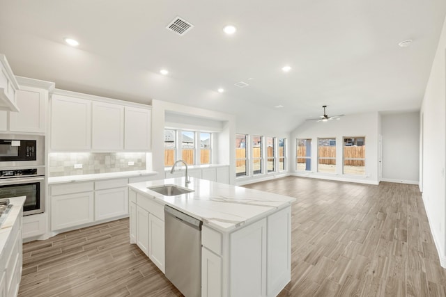 kitchen featuring sink, ceiling fan, white cabinetry, stainless steel appliances, and a center island with sink