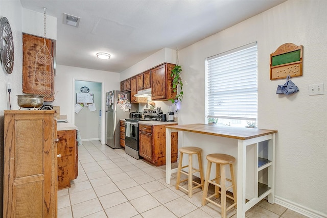 kitchen featuring a breakfast bar, light tile patterned flooring, and stainless steel appliances