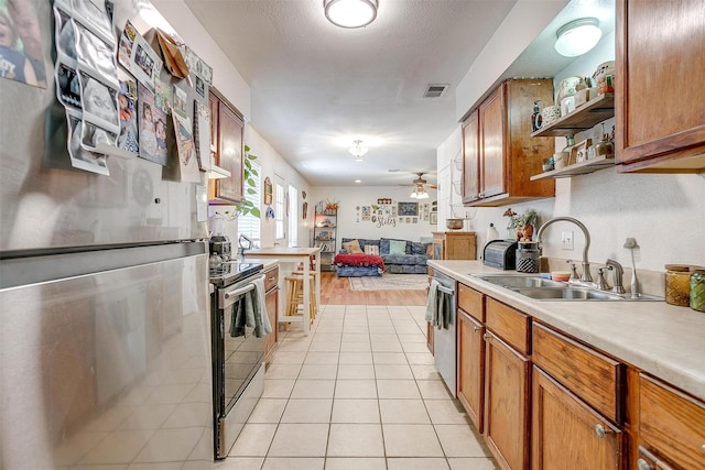 kitchen with ceiling fan, sink, a textured ceiling, light tile patterned floors, and appliances with stainless steel finishes