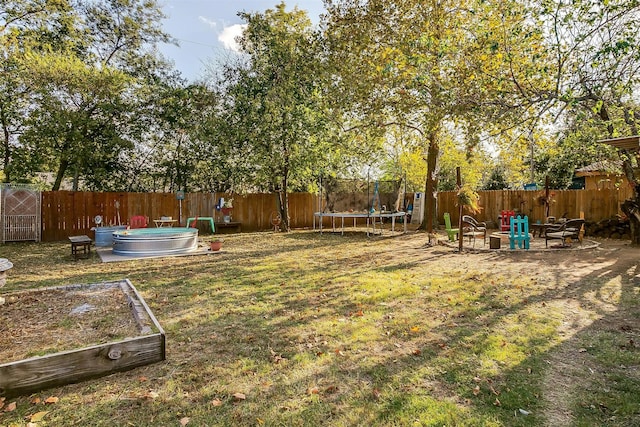 view of yard with an outdoor fire pit and a trampoline