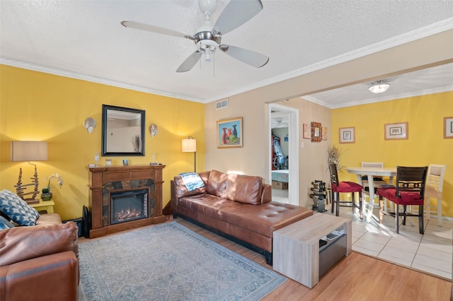 living room featuring a textured ceiling, light hardwood / wood-style flooring, ceiling fan, and crown molding