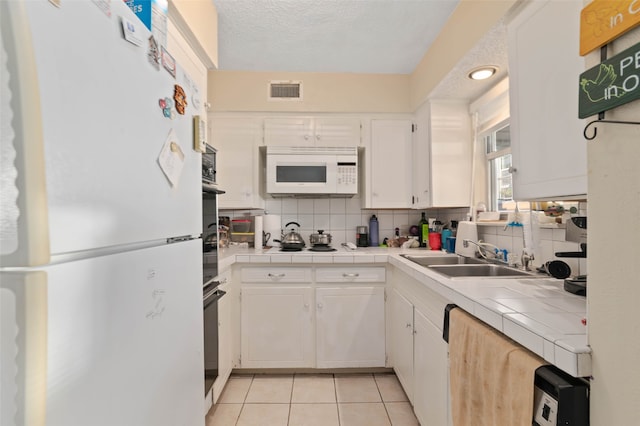 kitchen featuring decorative backsplash, white appliances, sink, white cabinetry, and tile counters