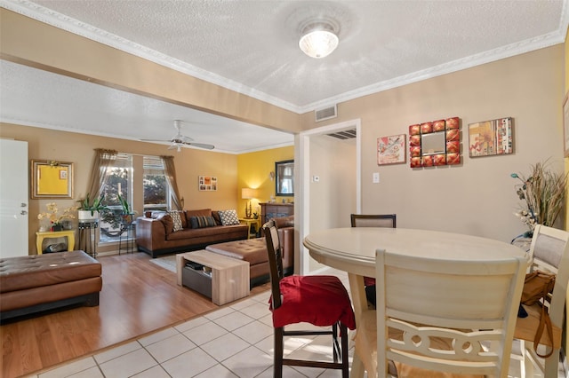 dining area featuring crown molding, ceiling fan, light hardwood / wood-style floors, and a textured ceiling