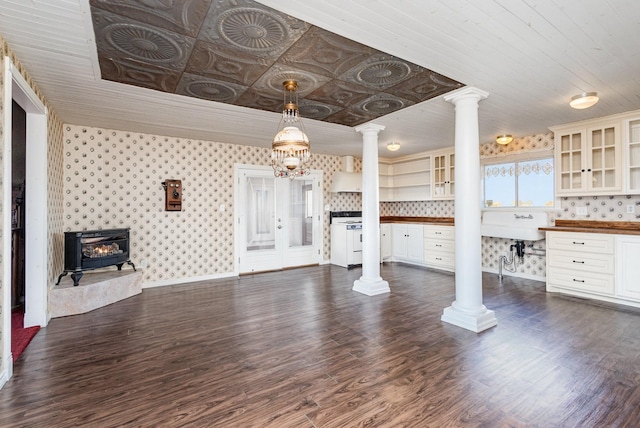 unfurnished living room featuring dark hardwood / wood-style flooring and ornate columns