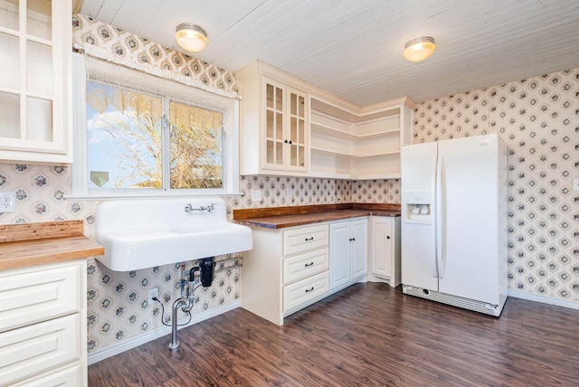 kitchen with dark wood-type flooring, white cabinets, sink, white fridge with ice dispenser, and butcher block countertops