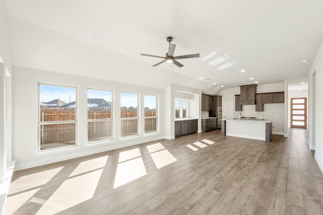 unfurnished living room featuring ceiling fan, light hardwood / wood-style floors, and vaulted ceiling