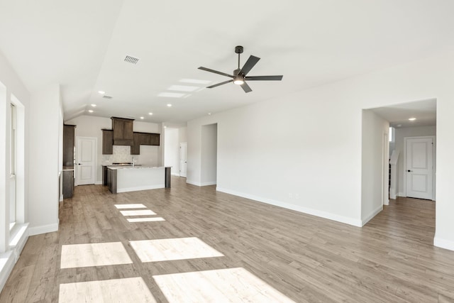 unfurnished living room with ceiling fan, lofted ceiling, and light wood-type flooring