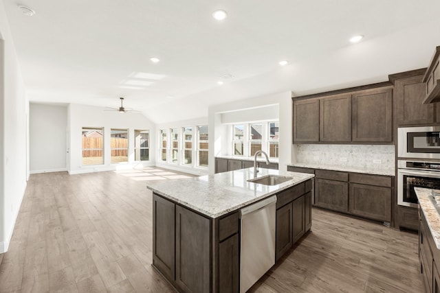 kitchen with appliances with stainless steel finishes, lofted ceiling, sink, backsplash, and dark brown cabinetry