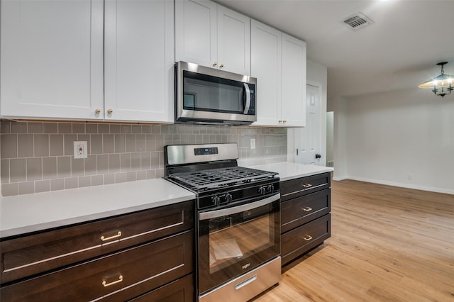 kitchen featuring white cabinets, stainless steel appliances, light hardwood / wood-style flooring, and tasteful backsplash