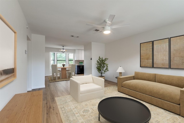 living room with light hardwood / wood-style flooring and ceiling fan with notable chandelier