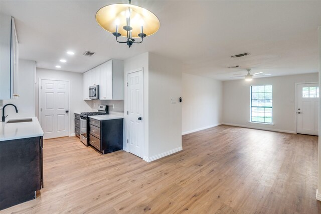 kitchen featuring white cabinets, ceiling fan with notable chandelier, stainless steel appliances, and light hardwood / wood-style floors