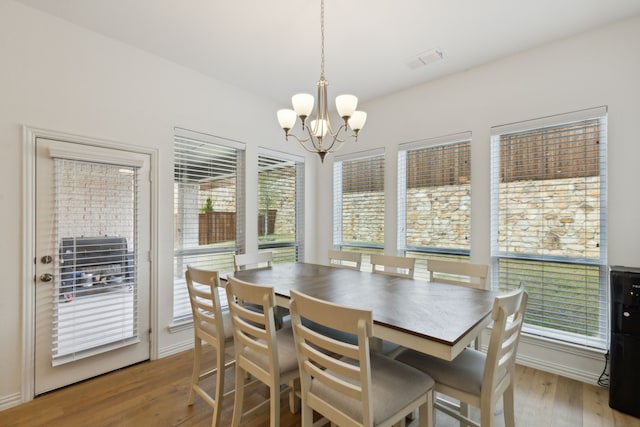 dining area with light hardwood / wood-style floors and a chandelier