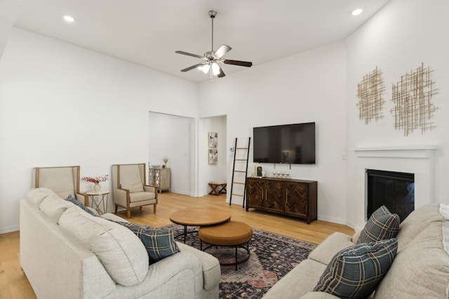 living room featuring hardwood / wood-style floors, a high ceiling, and ceiling fan