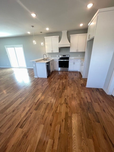 kitchen with stainless steel appliances, sink, white cabinets, decorative light fixtures, and premium range hood