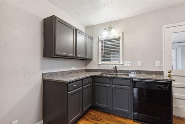 kitchen featuring dark wood-type flooring, sink, gray cabinets, dishwasher, and dark stone counters