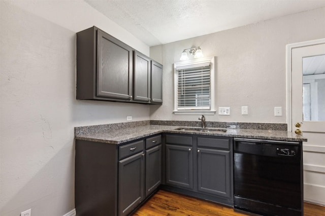 kitchen featuring dark countertops, a sink, dishwasher, gray cabinets, and dark wood-type flooring