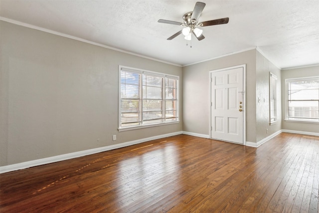 interior space featuring ceiling fan, wood-type flooring, a textured ceiling, baseboards, and ornamental molding