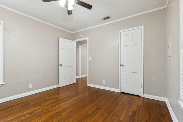 unfurnished bedroom with ceiling fan, visible vents, wood finished floors, baseboards, and ornamental molding