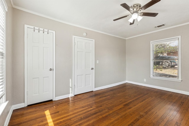 unfurnished room with a ceiling fan, visible vents, baseboards, ornamental molding, and dark wood-type flooring