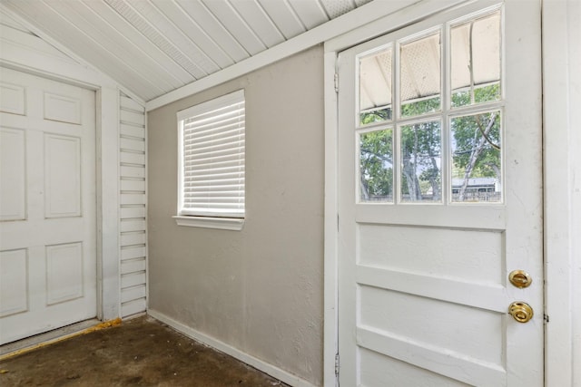 entryway with baseboards, concrete flooring, and vaulted ceiling