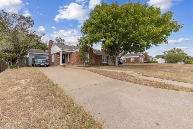 single story home with concrete driveway, brick siding, and a chimney