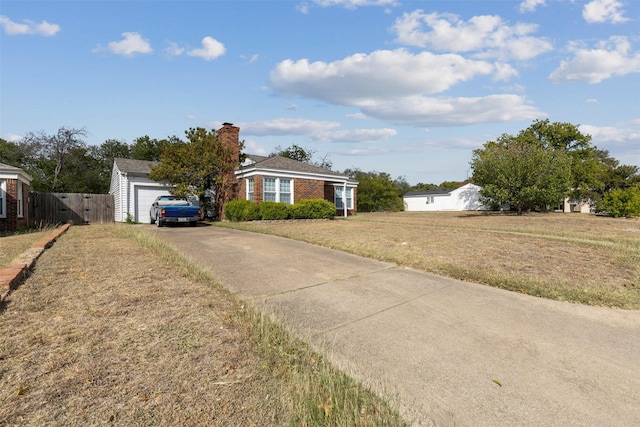 ranch-style house featuring driveway, a chimney, brick siding, fence, and a front lawn