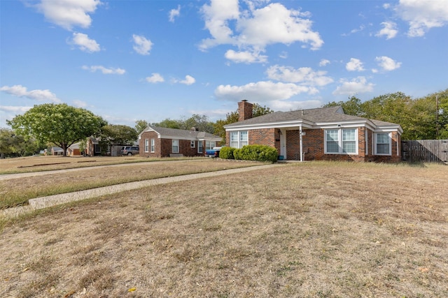 ranch-style home with fence, a chimney, a front lawn, and brick siding