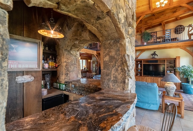 bar with beam ceiling, high vaulted ceiling, and light tile patterned floors