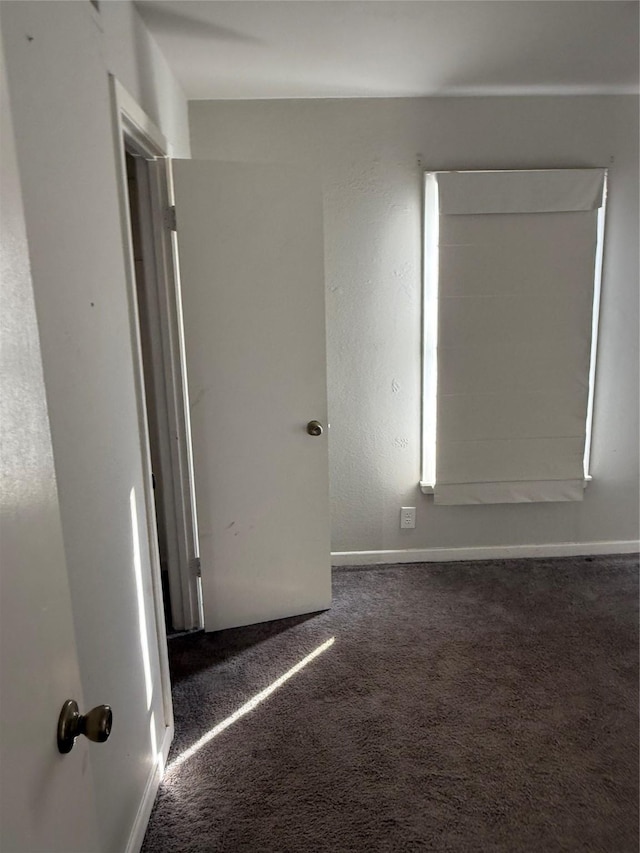 spare room featuring dark colored carpet