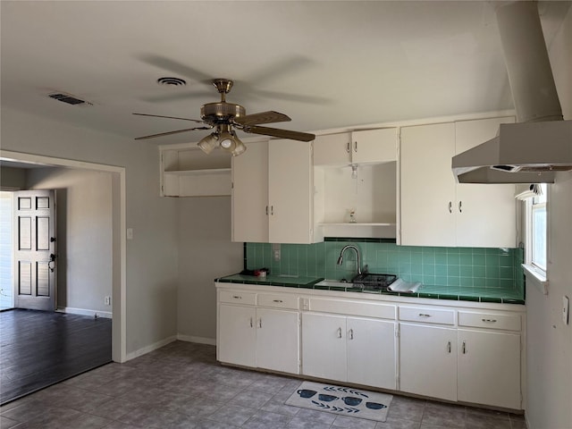 kitchen featuring backsplash, white cabinets, sink, tile counters, and island exhaust hood