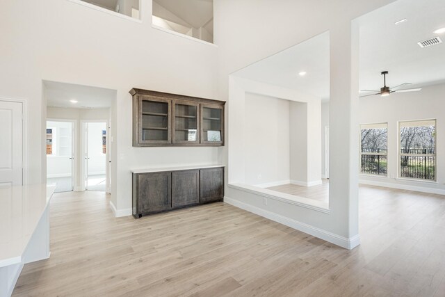 interior space featuring a towering ceiling, light hardwood / wood-style flooring, and ceiling fan
